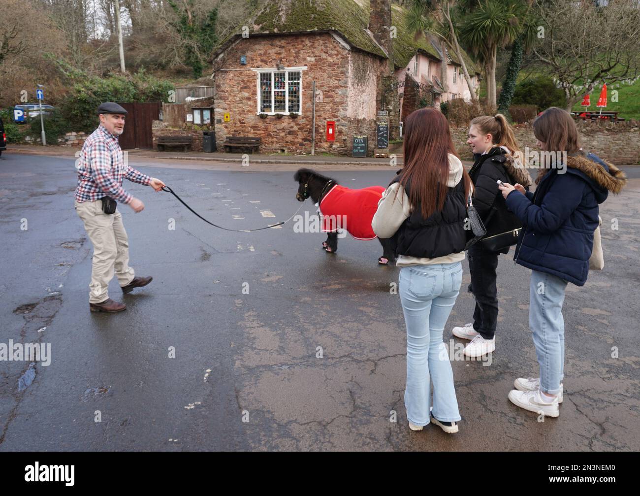 Cockington, UK. 03rd Feb, 2023. The Shetland pony Patrick, unofficial mayor of the English village of Cockington, and his owner Kirk Petrakis (l) are on the move in the village, the attention of passers-by is certain for them. When the mayor of Cockington makes his rounds, you can hear his hooves clattering from afar - because at the head of the English village of Cockington is a Shetland pony. But not everyone likes it. (to dpa 'Mayor in fluffy - How a pony rules an English village') Credit: Larissa Schwedes/dpa/Alamy Live News Stock Photo