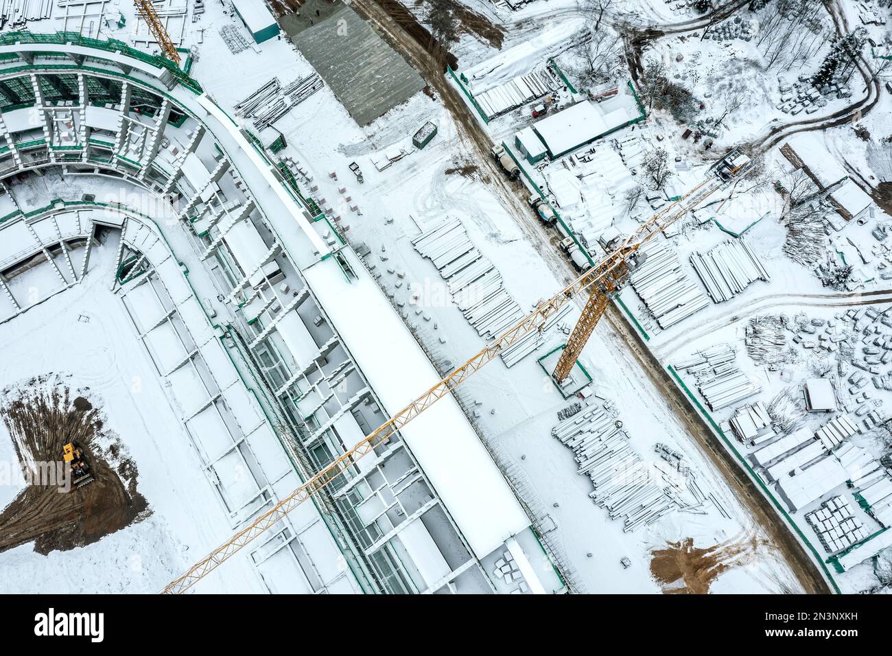 aerial top view of building site, covered with snow with yellow crane. new stadium under construction. Stock Photo