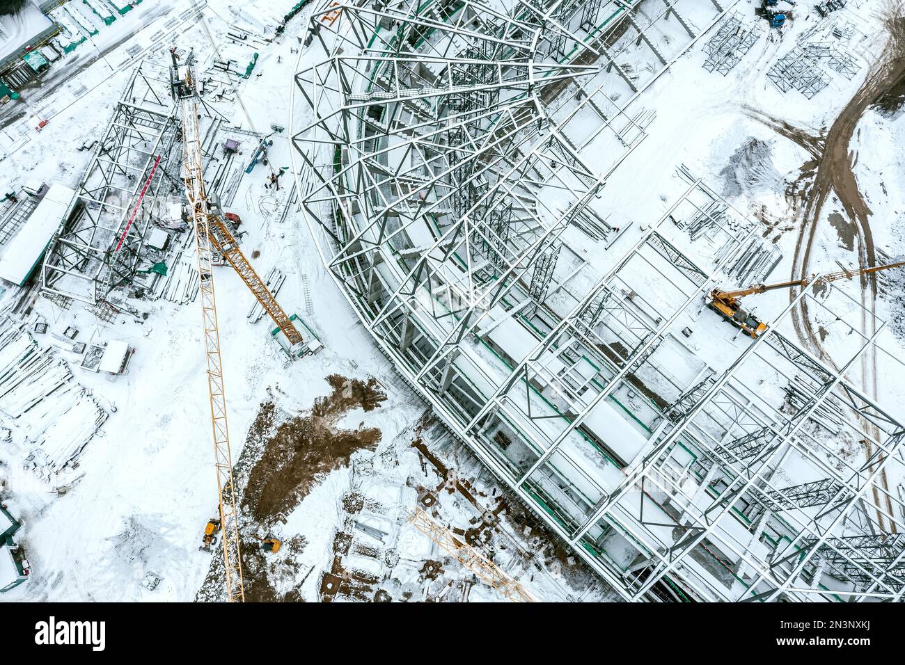 aerial top view of snow-covered building site with yellow crane. new ...