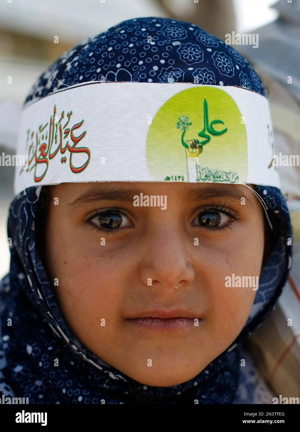 A Yemeni girl wears a headband with Arabic writing that reads,"Imam Ali