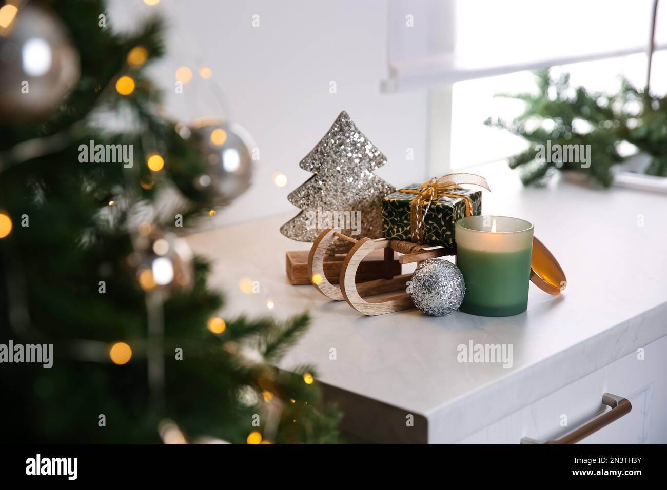 https://c8.alamy.com/comp/2N3TH3Y/toy-sleigh-with-gift-box-decorative-christmas-tree-candle-and-ball-on-white-countertop-indoors-2N3TH3Y.jpg