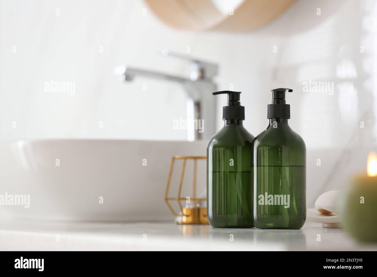 Green soap dispensers on countertop near sink in bathroom. Space for