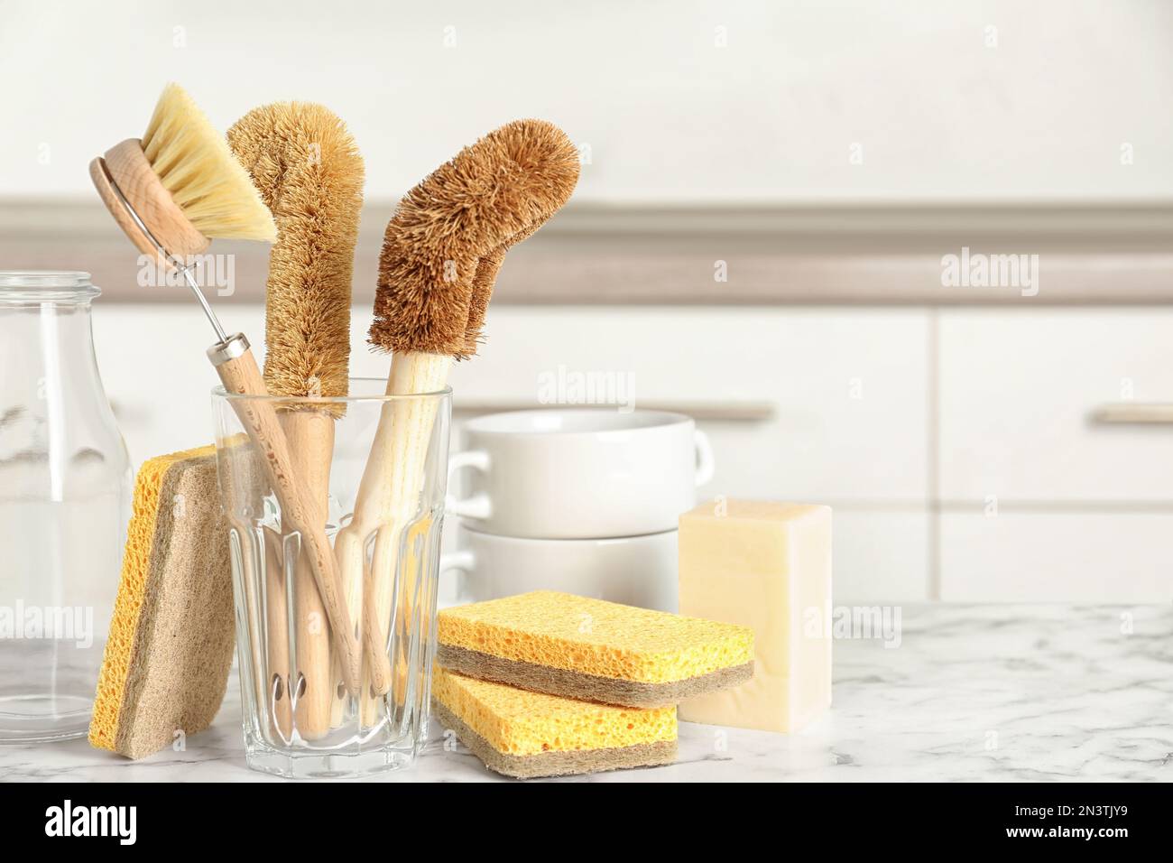 Cleaning tools on white marble table in kitchen, space for text. Dish ...