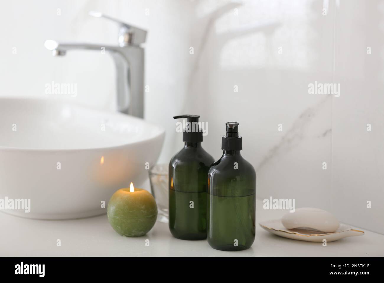 Green soap dispensers on countertop near sink in bathroom Stock Photo