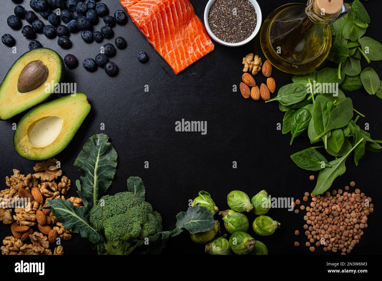 Healthy food background with good fat sources, ingredients rich in Omega fatty acids: salmon fillet, vegetables, berries, nuts, seeds, olive oil Stock Photo