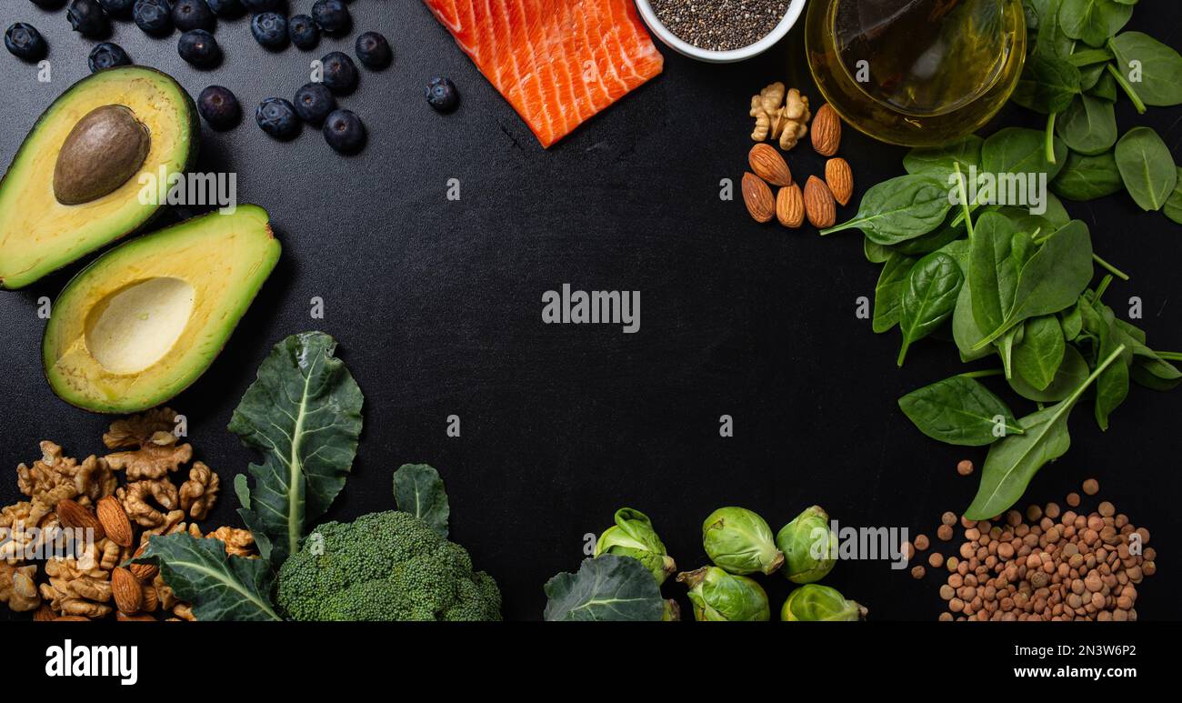 Healthy food background with good fat sources, ingredients rich in Omega fatty acids: salmon fillet, vegetables, berries, nuts, seeds, olive oil Stock Photo
