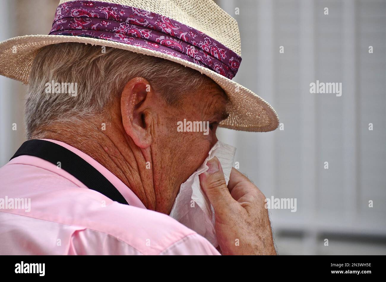 Old man with straw hat from the side blows his nose Stock Photo - Alamy