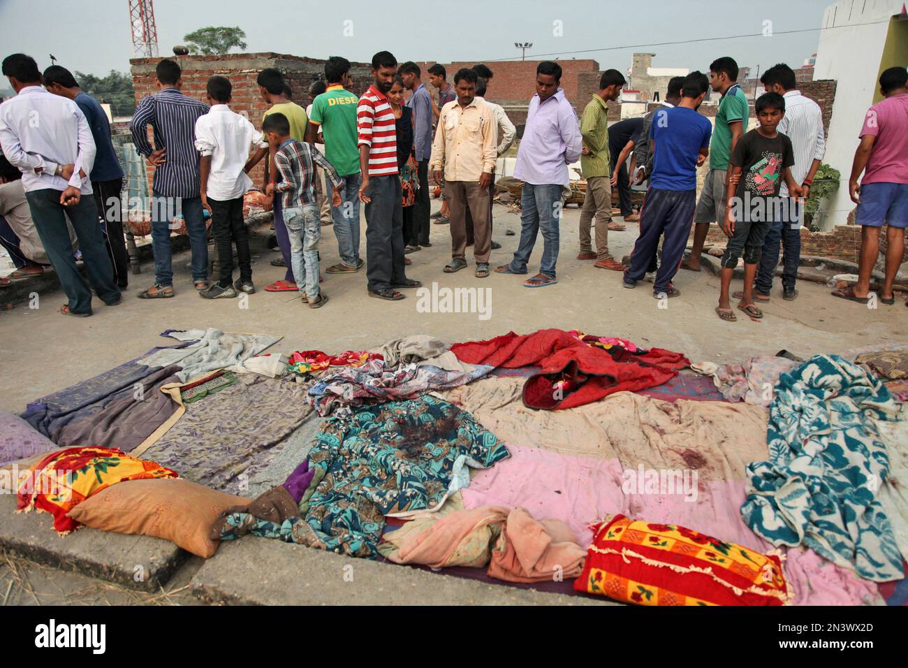 Indian villagers gather near bed sheets stained with blood in alleged