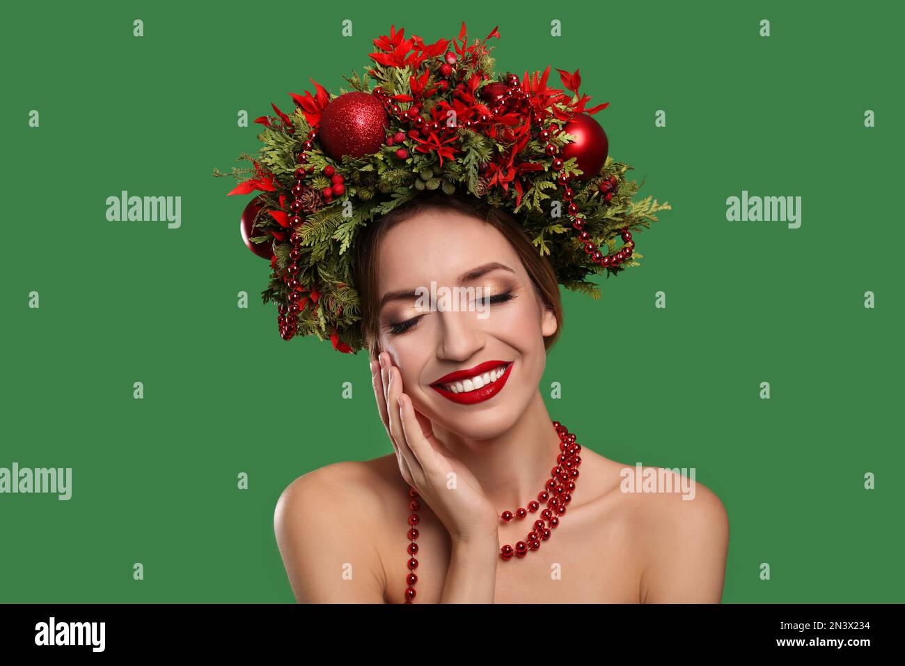 Beautiful young woman wearing Christmas wreath on green background Stock Photo