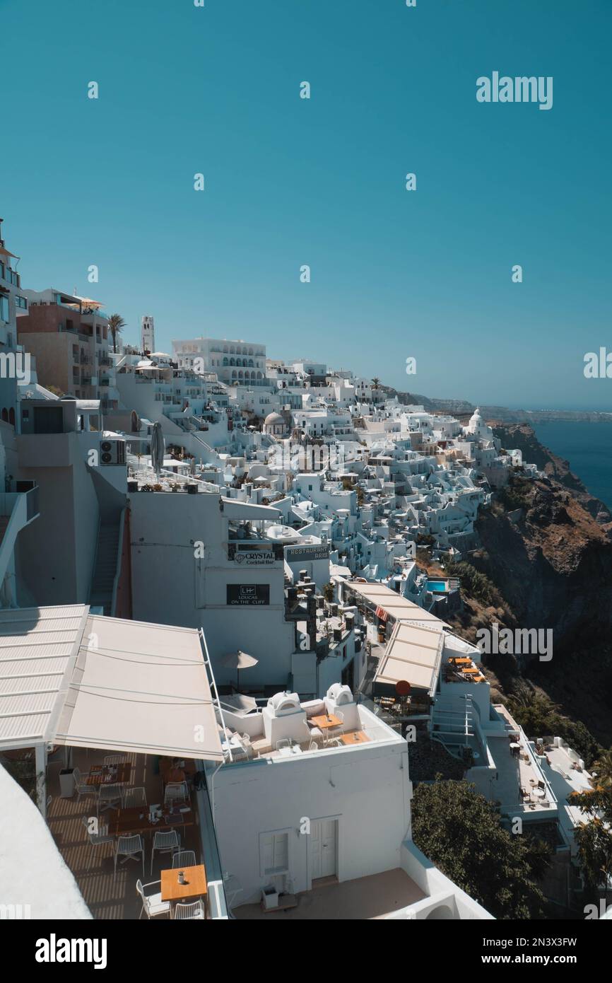 A vertical areal view of Fira in Santorini with a blue sky in the background, Greece Stock Photo