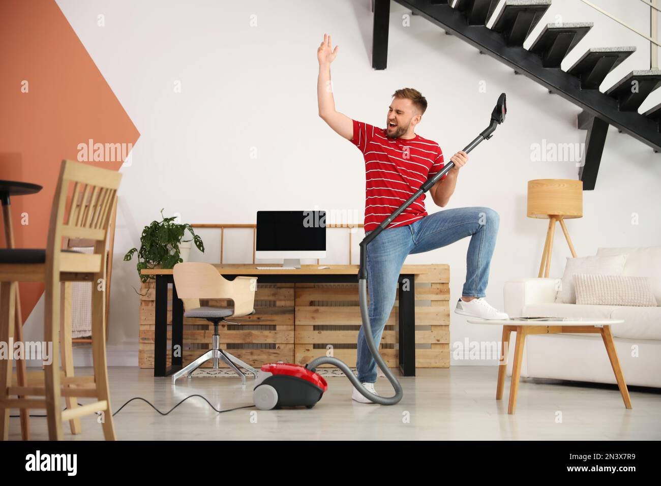 Young man having fun while vacuuming at home Stock Photo