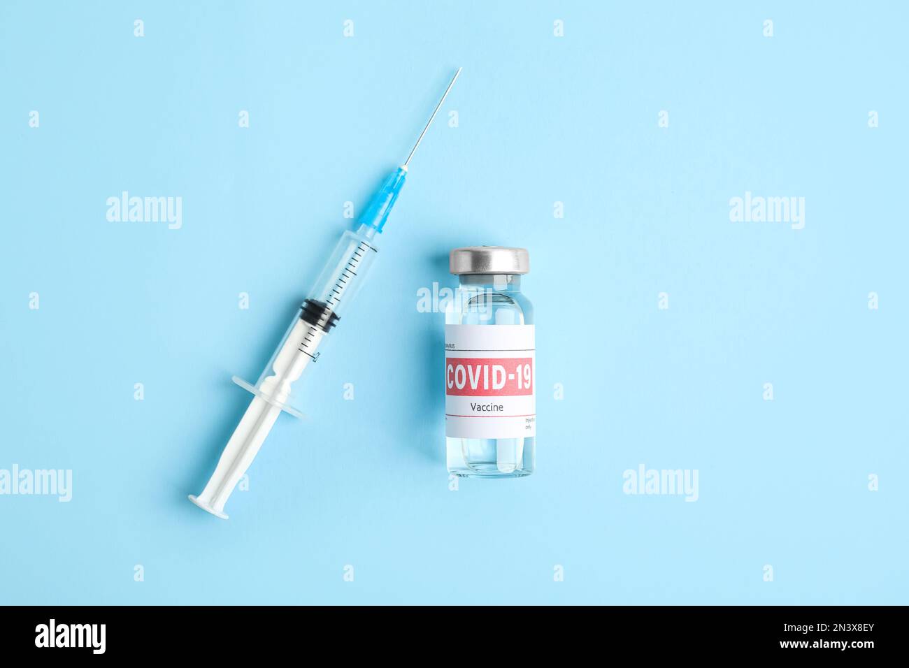 Vial with coronavirus vaccine and syringe on light blue background ...