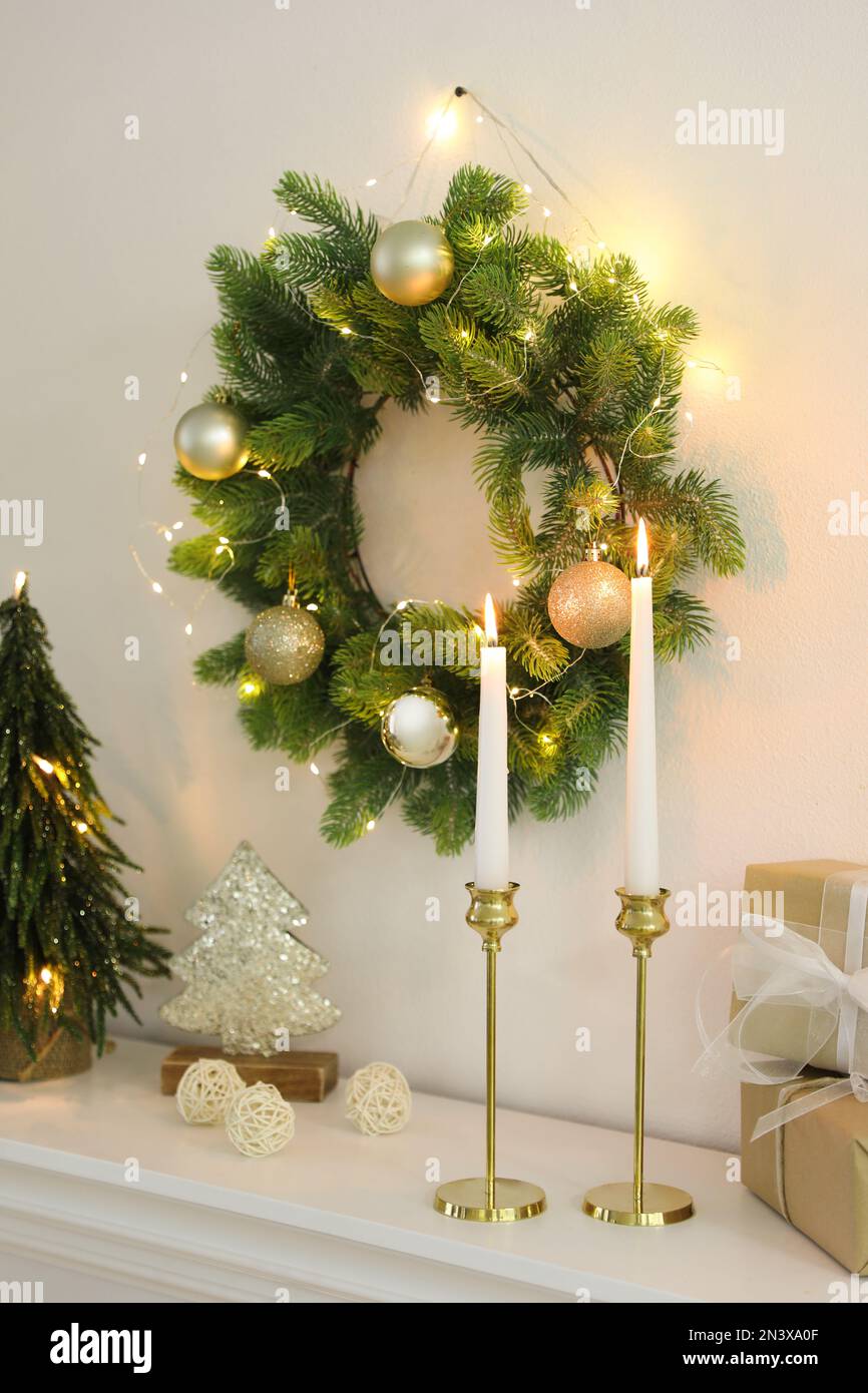 Burning candles on mantelpiece in decorated room. Christmas celebration