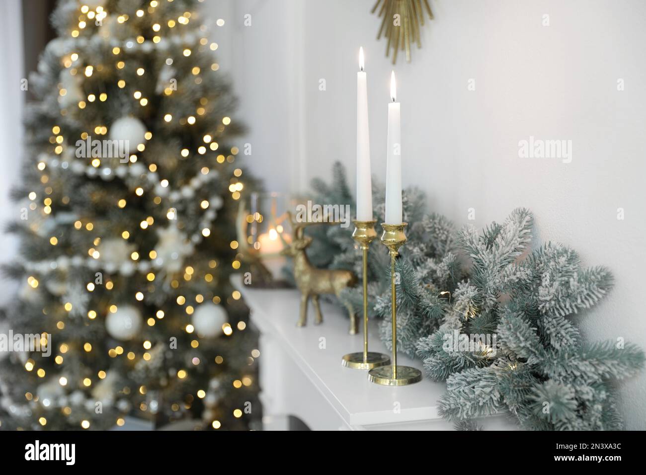Burning candles on mantelpiece in decorated room. Christmas celebration