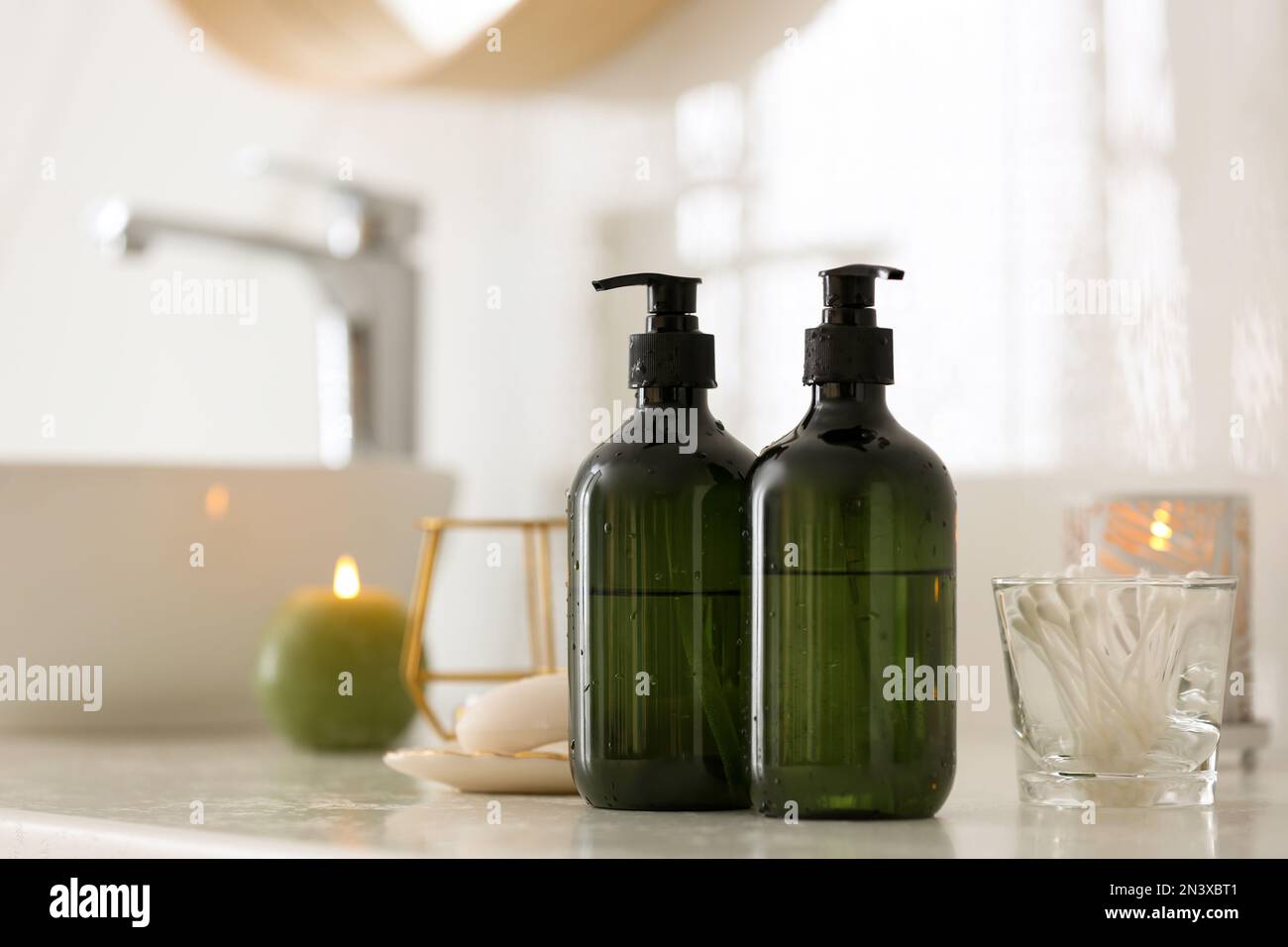 Green soap dispensers on countertop near sink in bathroom. Space for