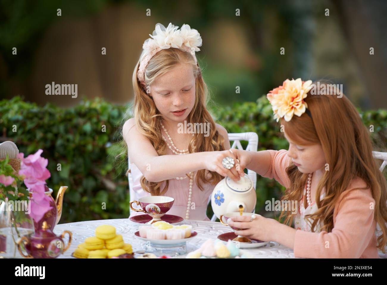 Garden tea time. Two young girls having a tea party in the backyard ...