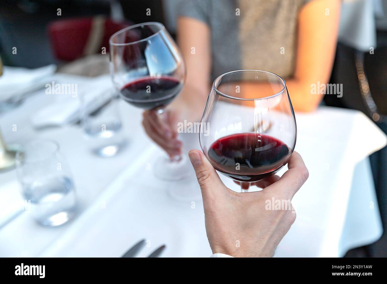 Couple of lovers with glasses of red wine sitting in restaurant Stock Photo