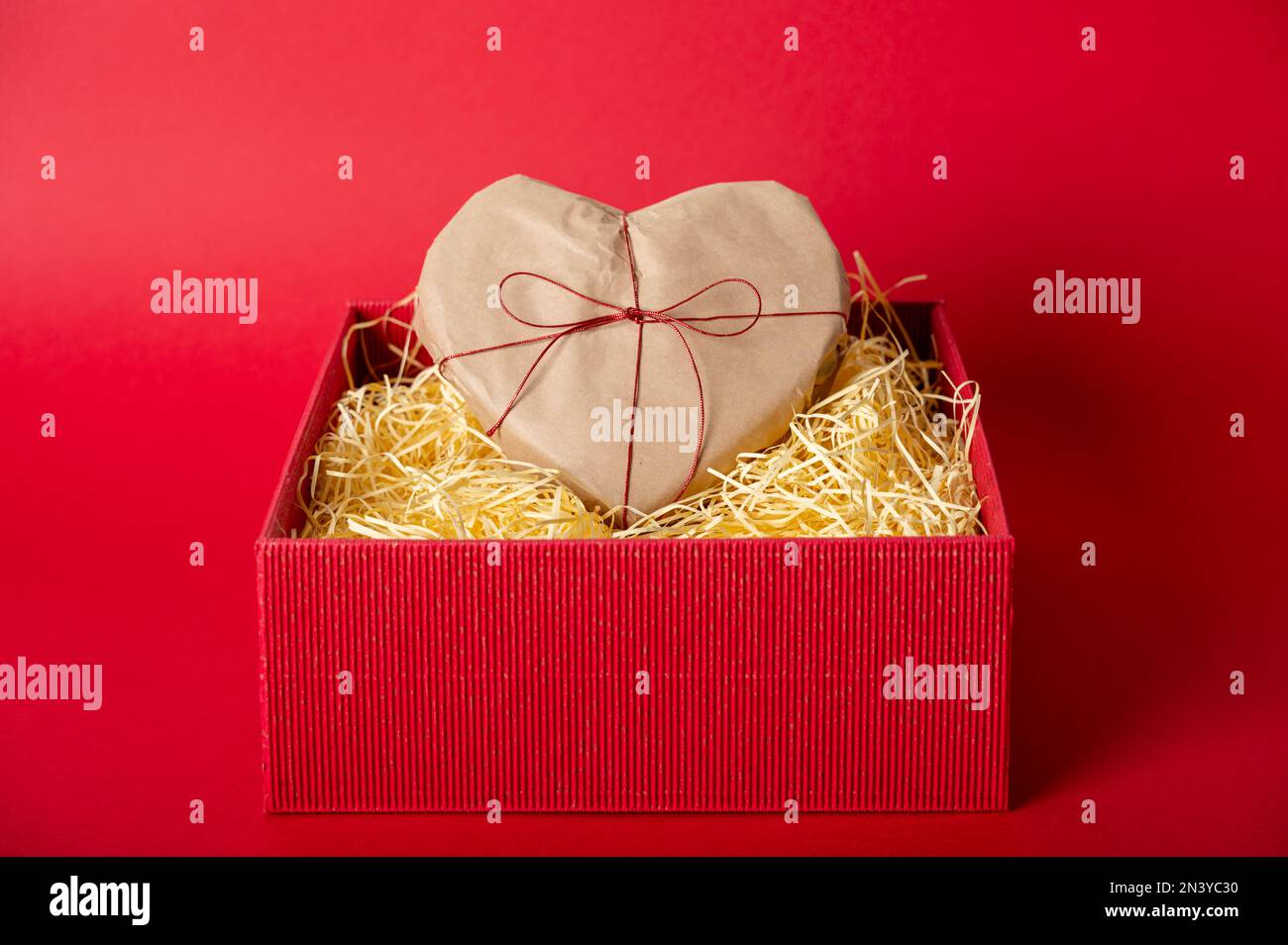 Heart shaped gift with bow in red box with shredder paper. Valentine's ...