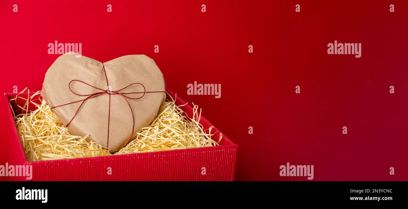 Heart shaped gift with bow in red box with shredder paper. Valentine's ...