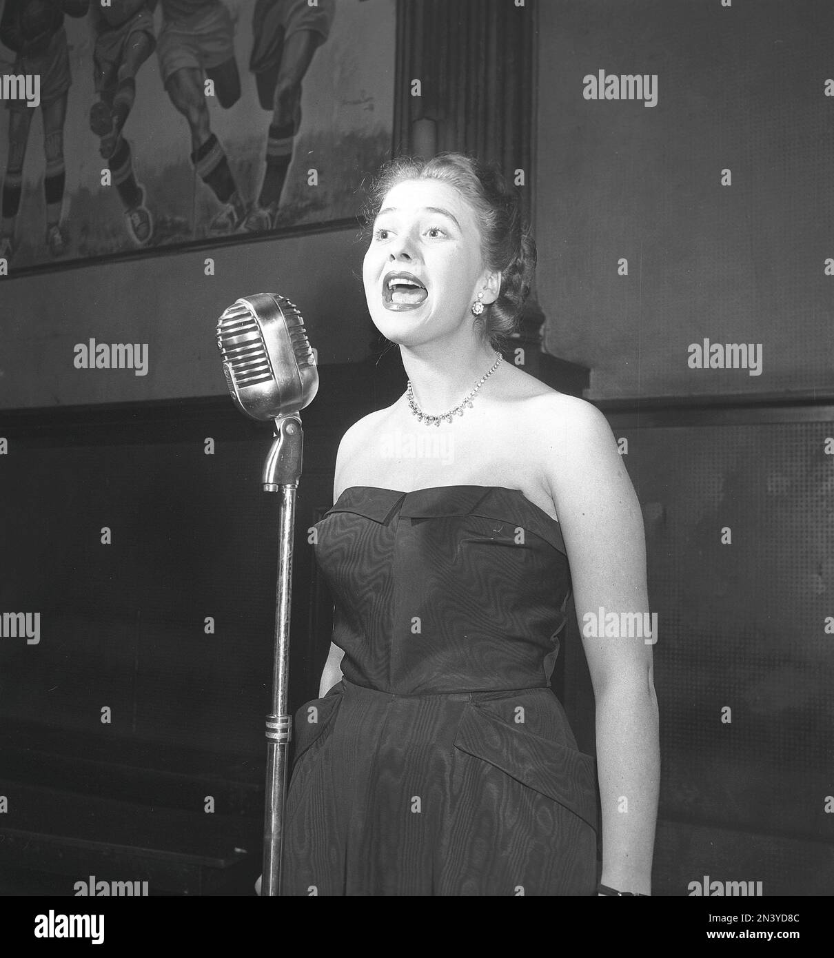 In the 1950s. A young woman seen singing on stage with a microphone in front of her at the dance establishment National shortened by the locals to Nalen. Stockholm Sweden 1952 Kristoffersson ref BF15-4 Stock Photo