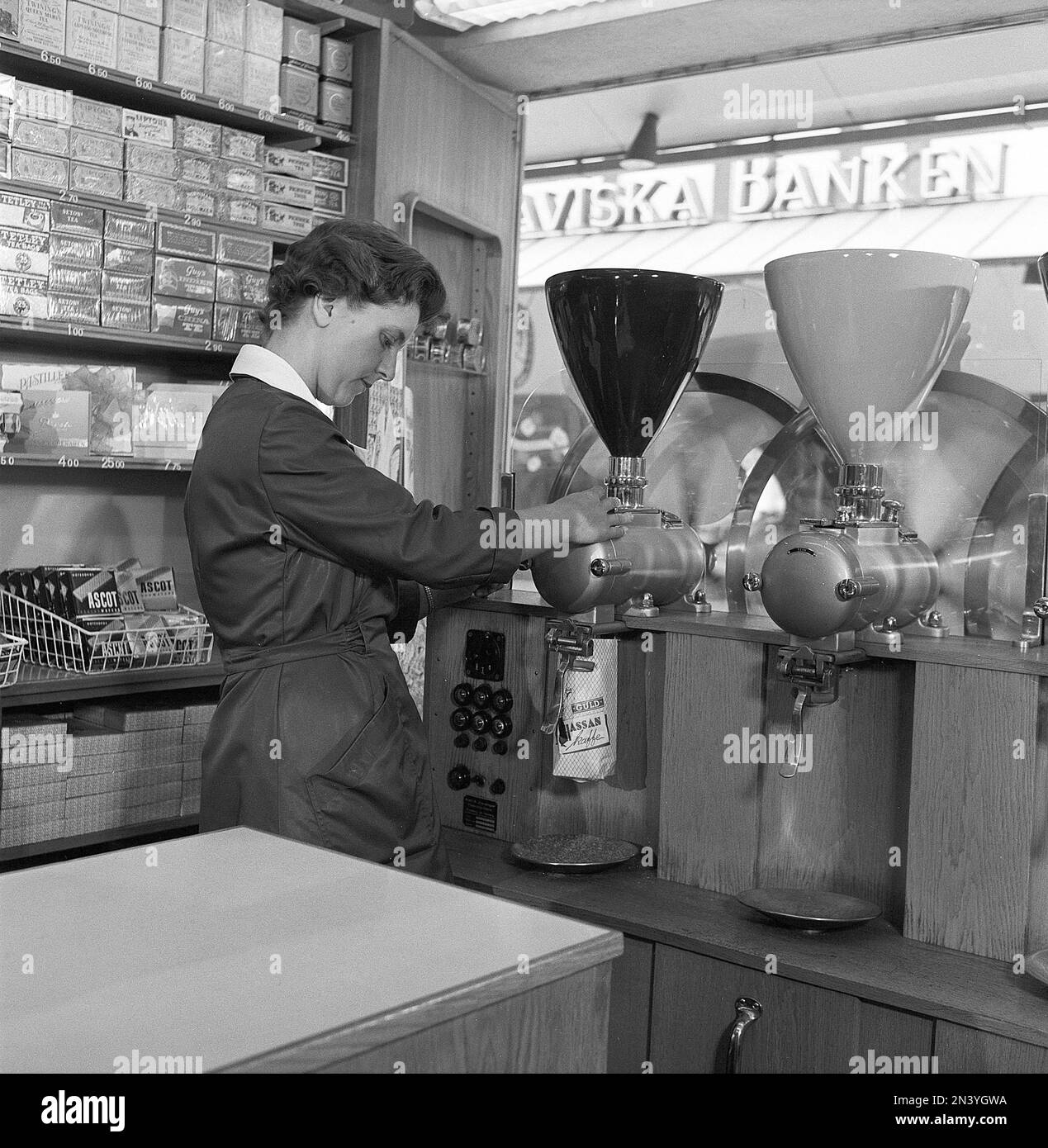 In the 1950s. A woman working in a store is seen grinding coffee beans into a paper bag.  Sweden 1958 ref BV100-5 Stock Photo