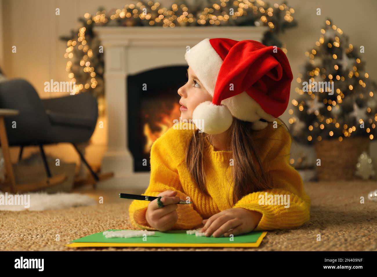Cute child writing letter to Santa Claus while lying on floor at home
