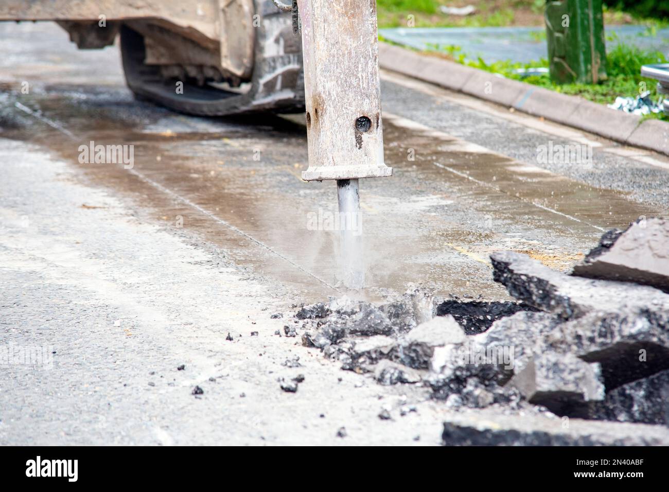 Excavator with hydraulic jack hammer breaking asphalt in preparation