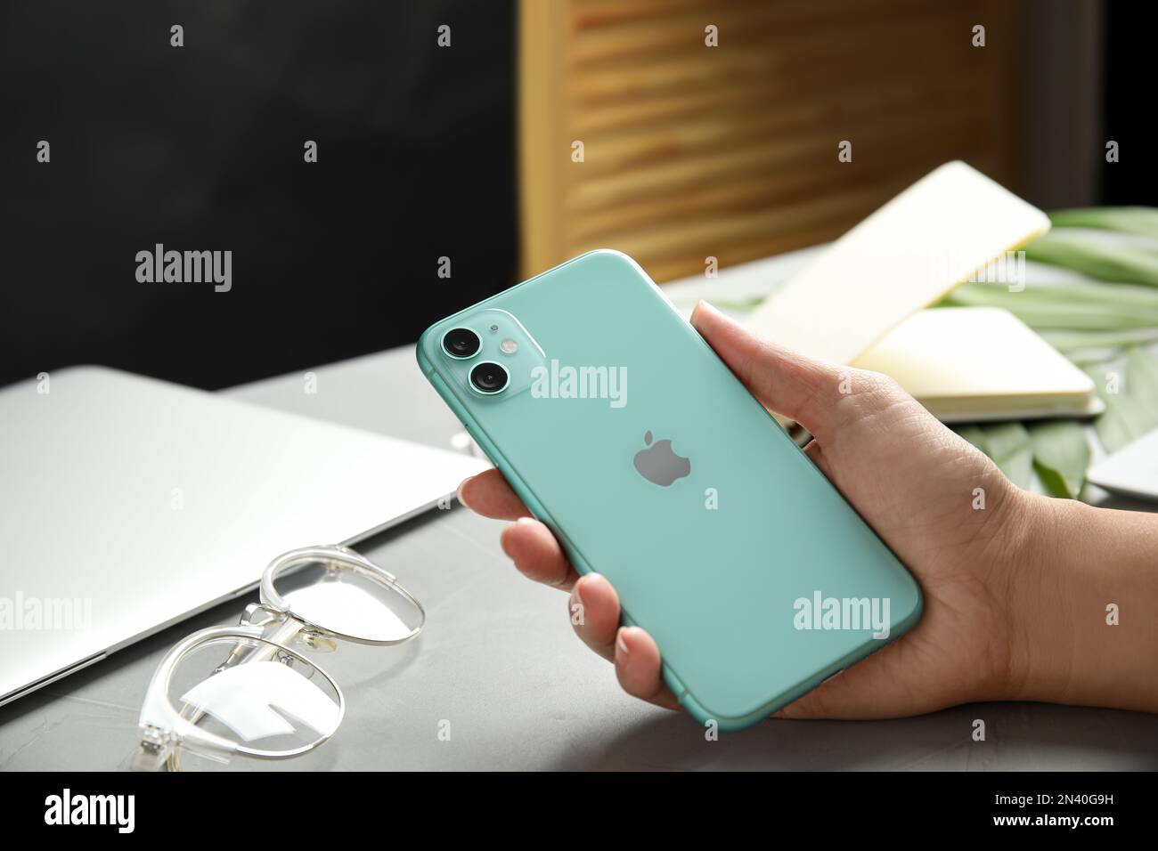 MYKOLAIV, UKRAINE - JULY 9, 2020: Woman holding Iphone 11 Green at table, closeup Stock Photo