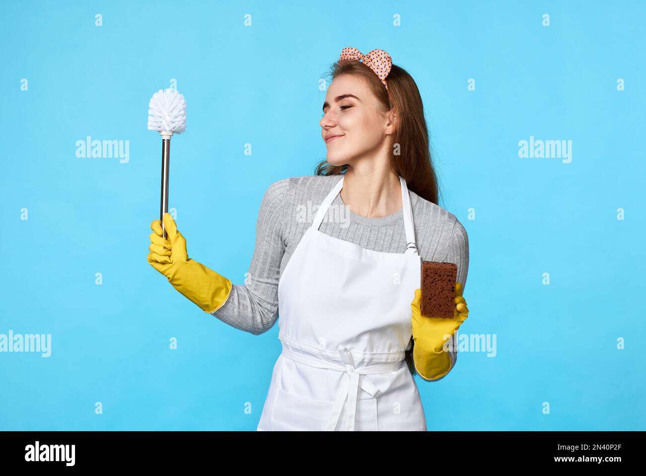 woman in rubber gloves and cleaner apron cleaning with sponge Stock