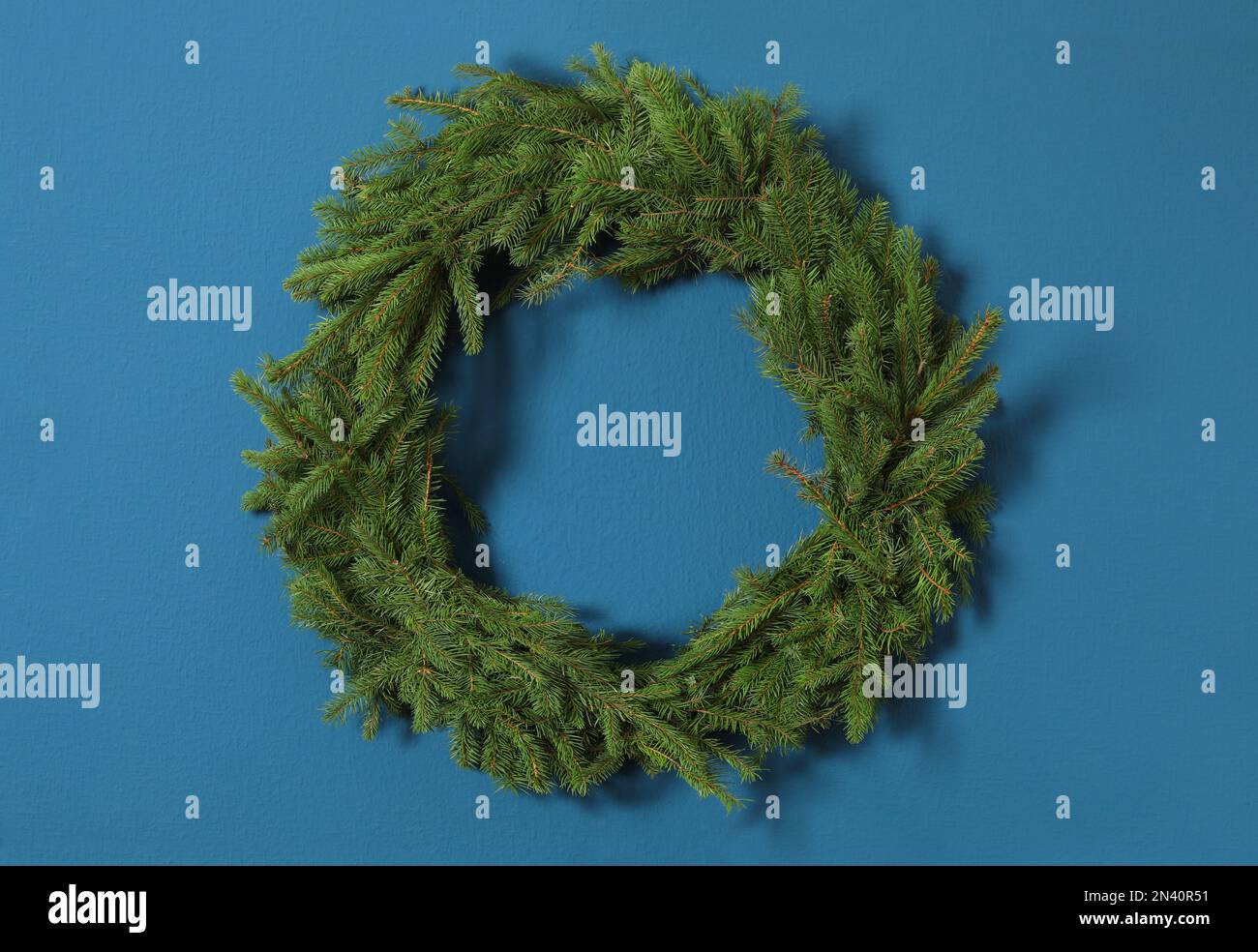 Christmas wreath made of fir branches on blue wall Stock Photo - Alamy
