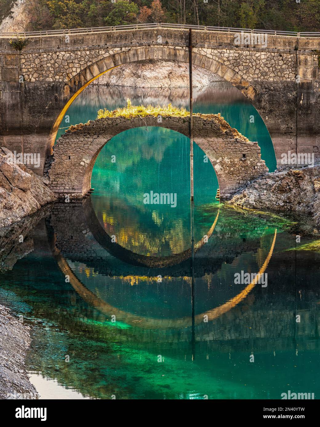 The autumn colors of the trees and two bridges are reflected in the ...
