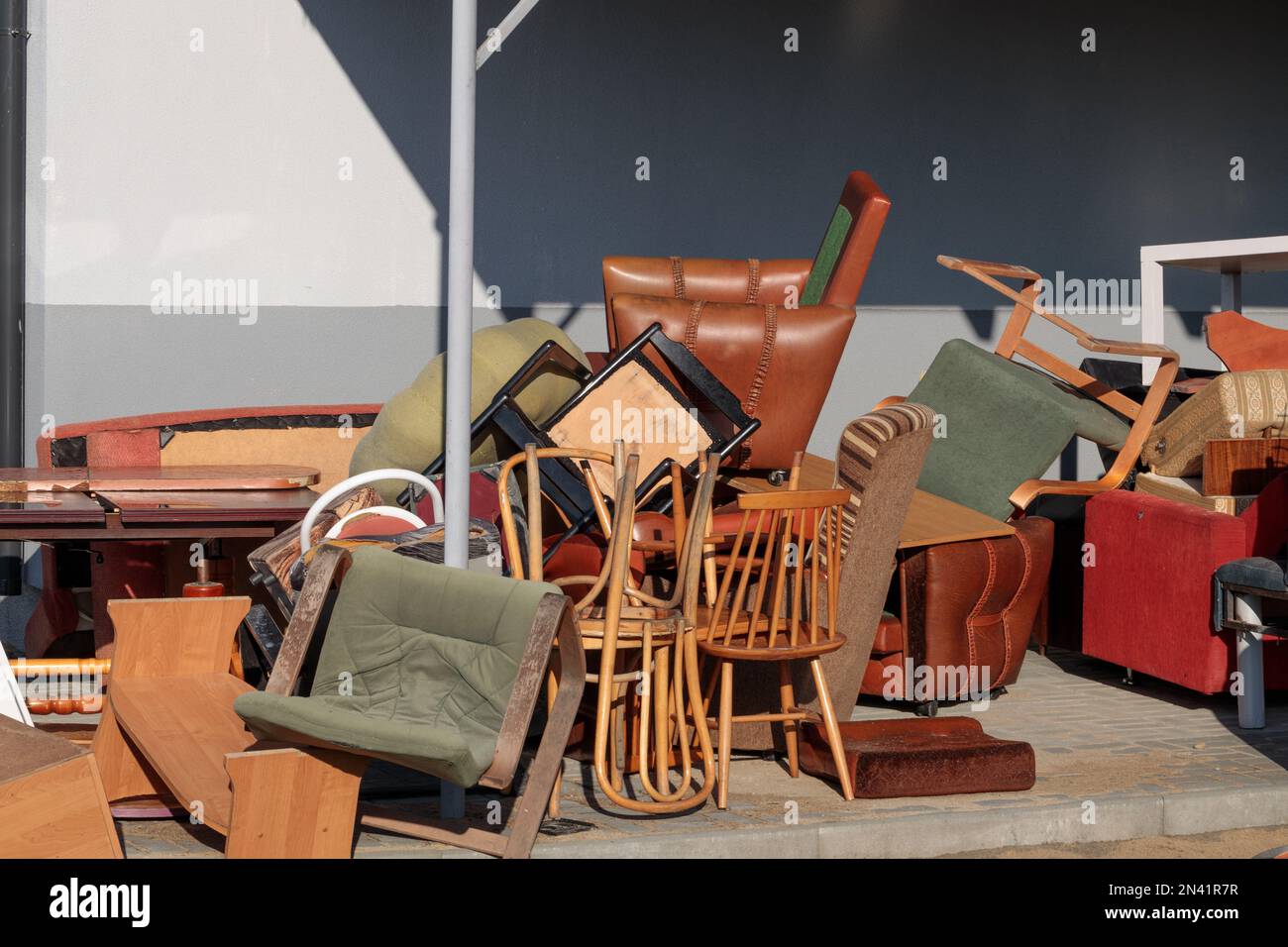 Old, damaged furniture at landfill close to brick house. Big problem