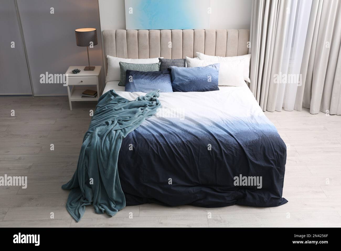 Comfortable bed with pillows and soft blanket in room. Stylish interior