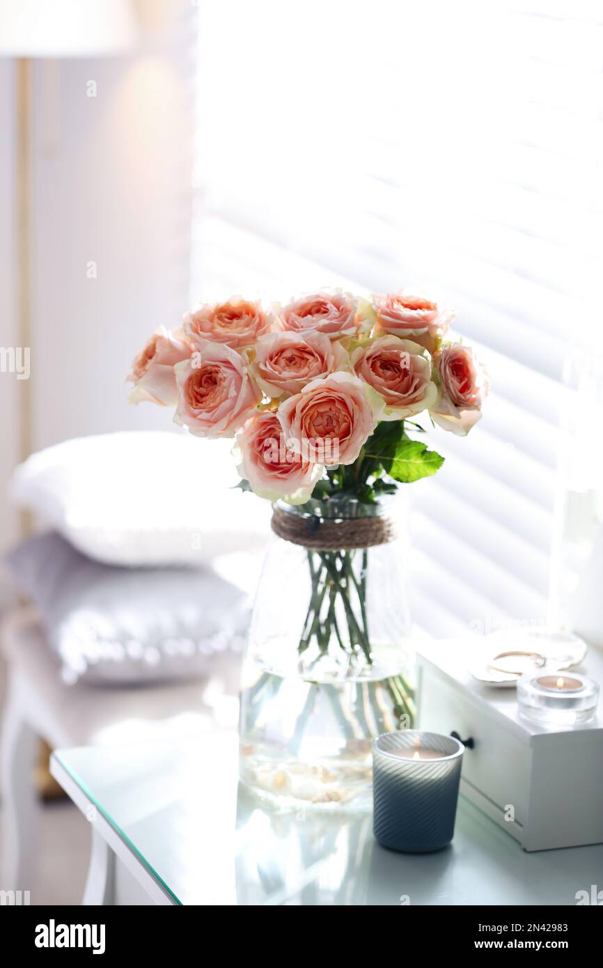 Glass vase with beautiful flowers on dressing table in modern room
