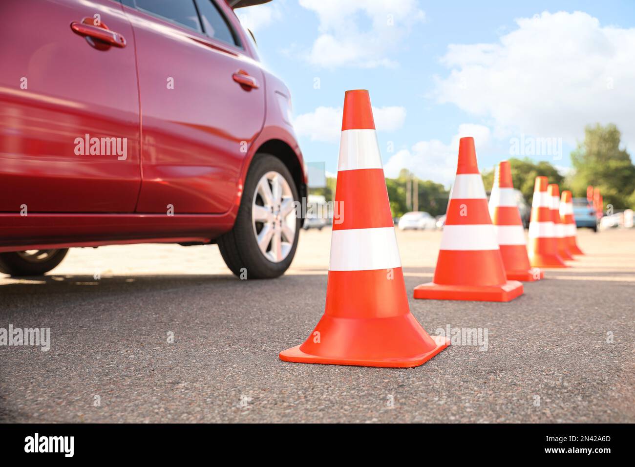Traffic cones near red car outdoors. Driving school exam Stock Photo
