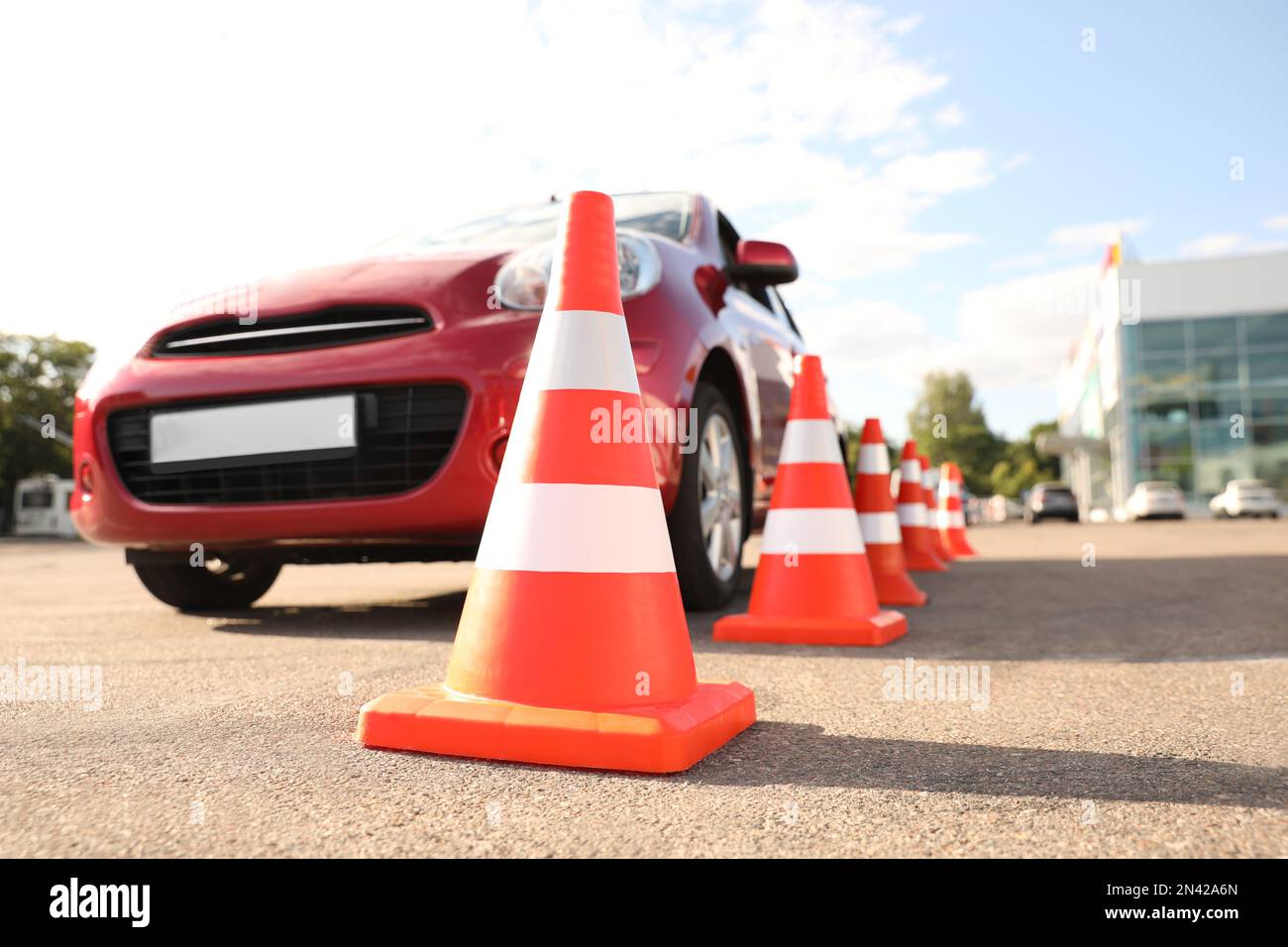 Traffic cones near red car outdoors. Driving school exam Stock Photo