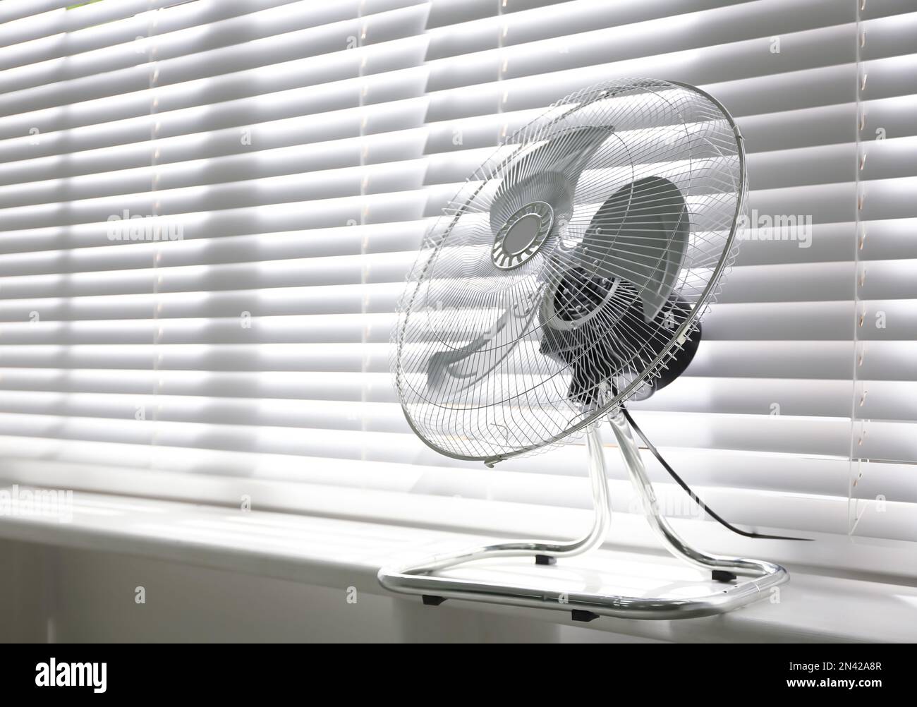 Modern electric fan on window sill indoors. Space for text Stock Photo