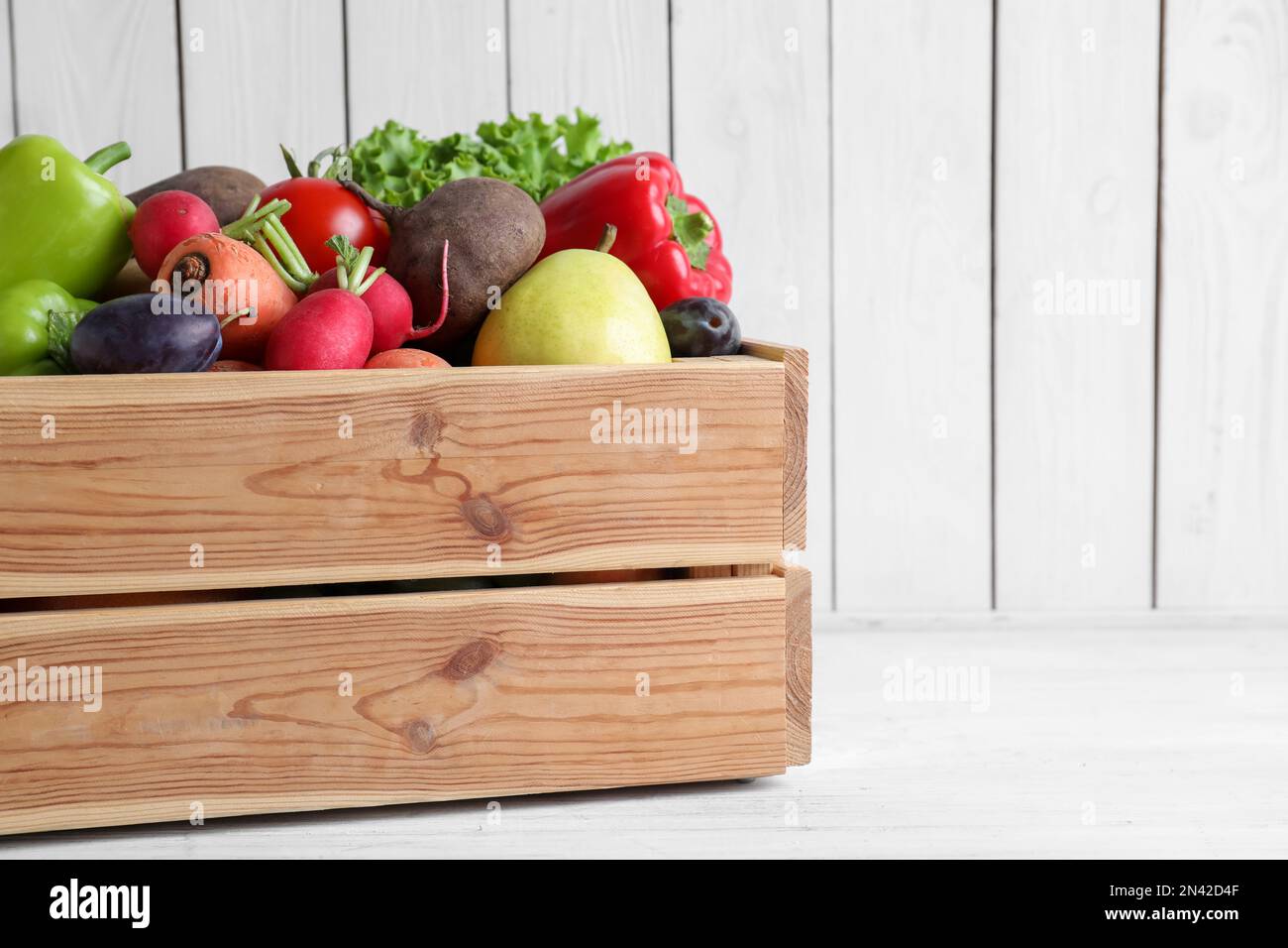 Crate full of different vegetables and fruits on white wooden table ...