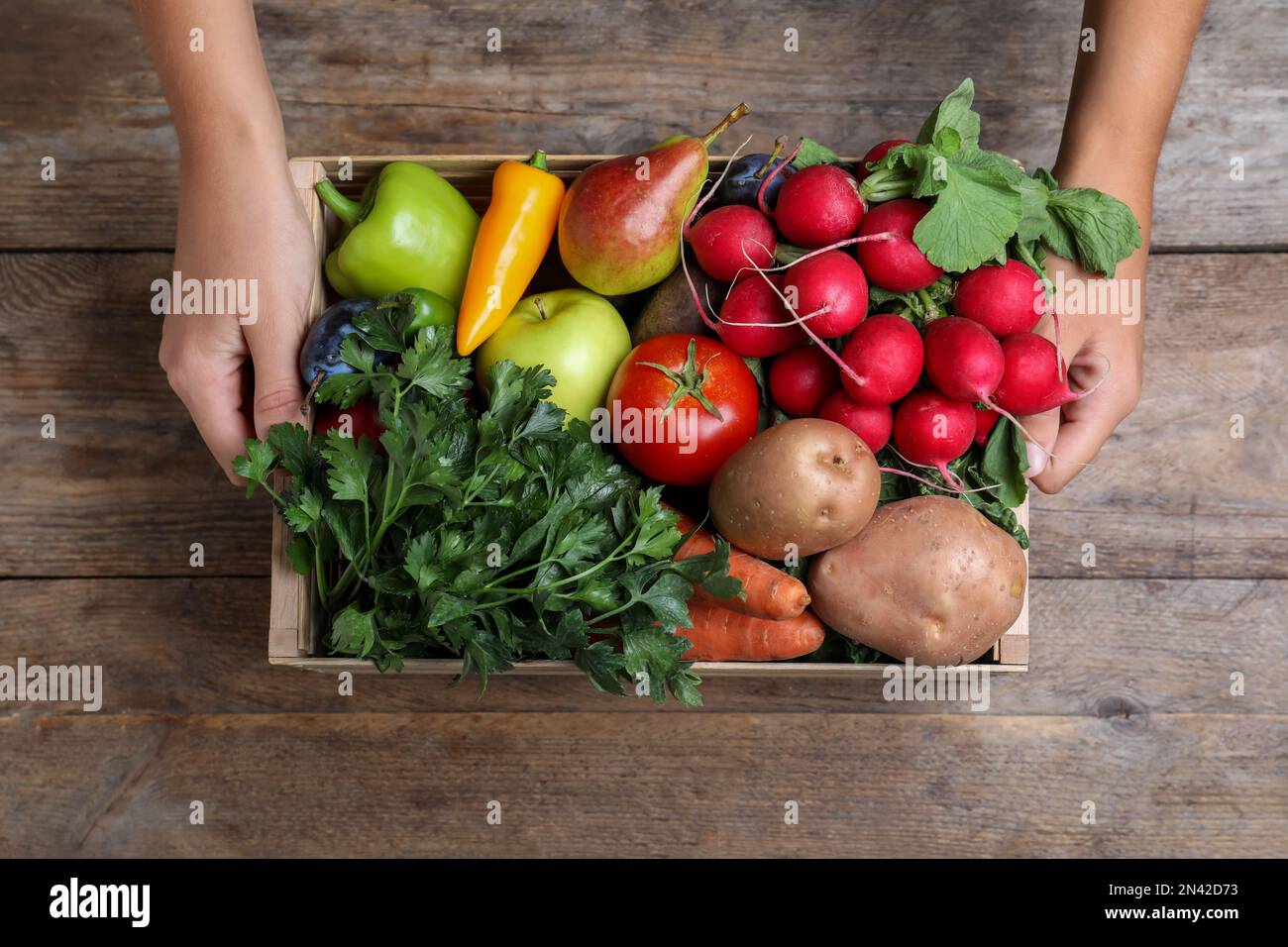 Farmer with crate full of different vegetables and fruits at wooden ...