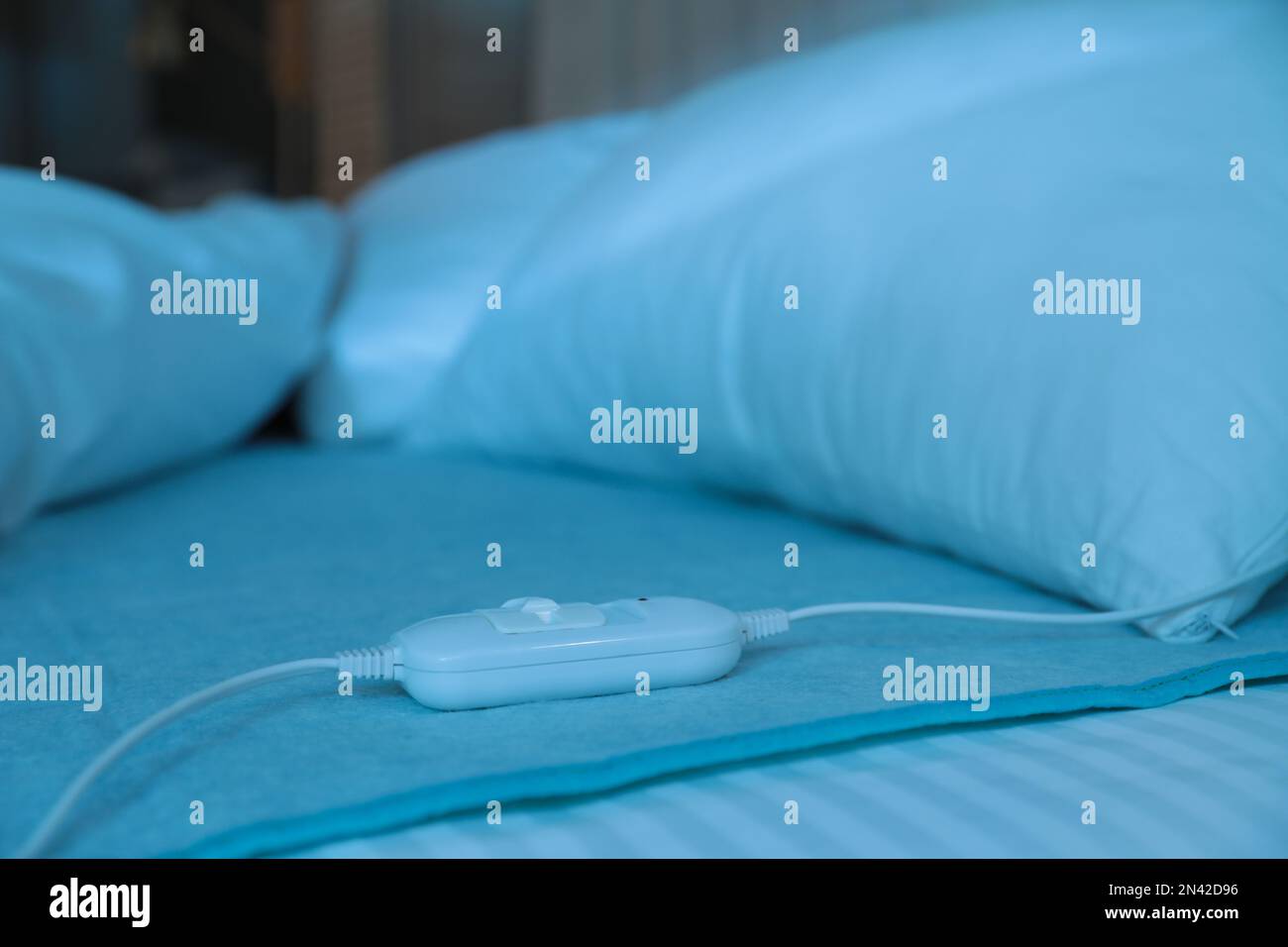 Bed with electric heating pad indoors at night Stock Photo