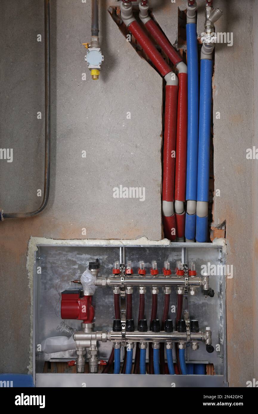 Underfloor heating system. Manifold with pipes in building Stock Photo