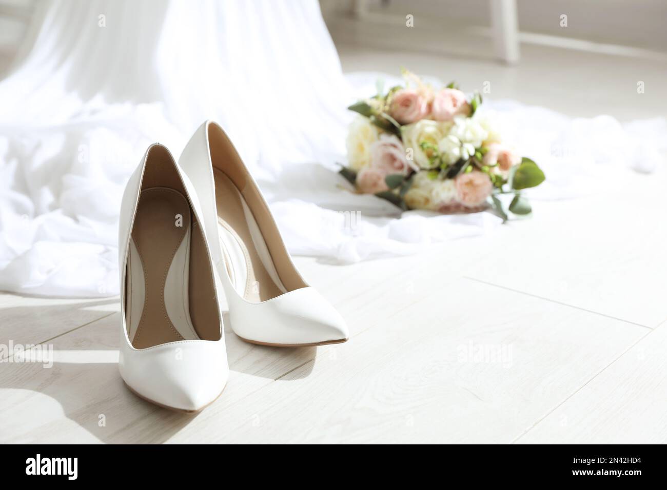 Pair of wedding high heel shoes on white wooden floor indoors Stock Photo