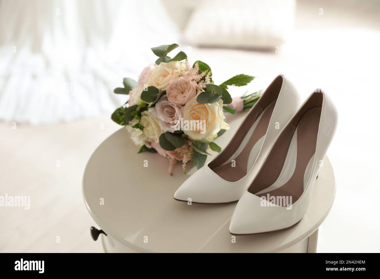 Pair of wedding high heel shoes and beautiful bouquet on white table Stock Photo