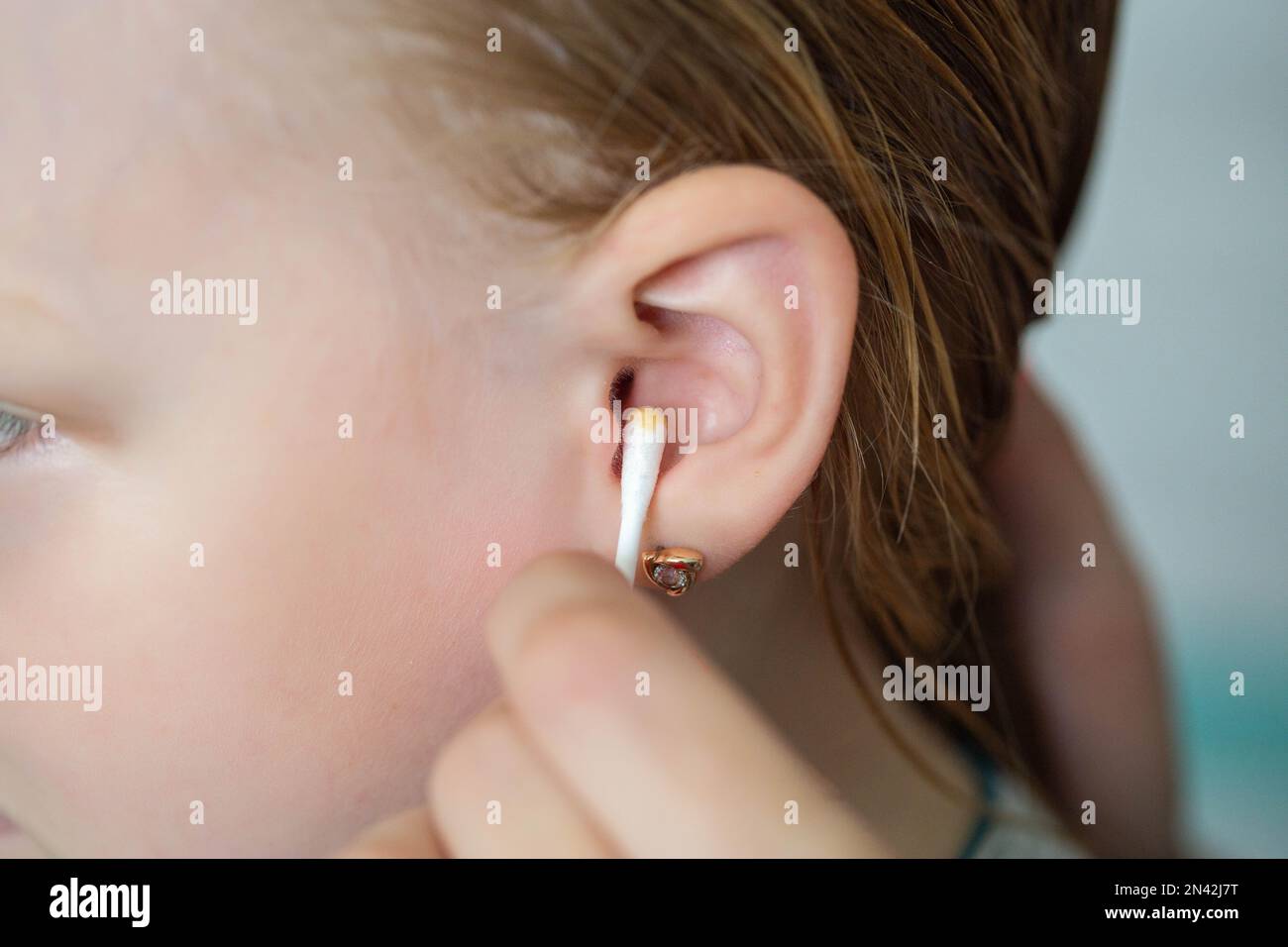 Cleaning a child's ear with a cotton swab from contamination of the ear