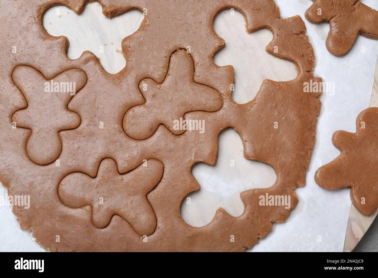 Making homemade Christmas cookies. Dough for gingerbread man on parchment, flat lay Stock Photo
