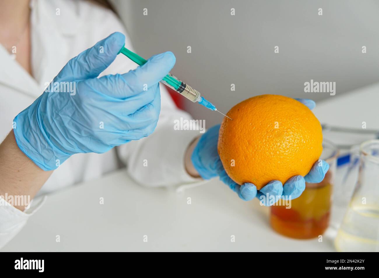 Scientist with syringe injects chemicals into an orange, Pesticides and
