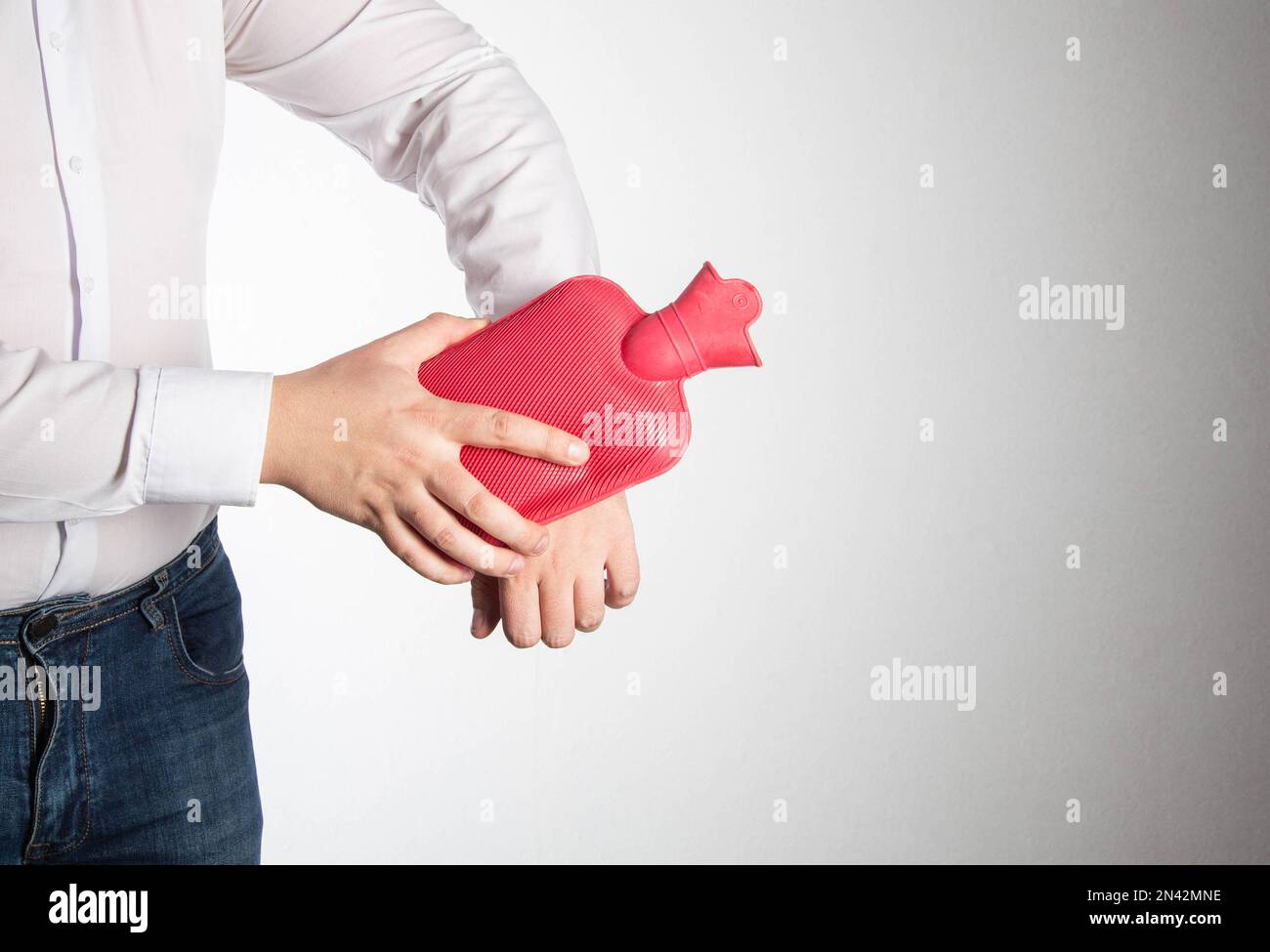 A man smoothes a red heating pad with hot water on his wrist joint to