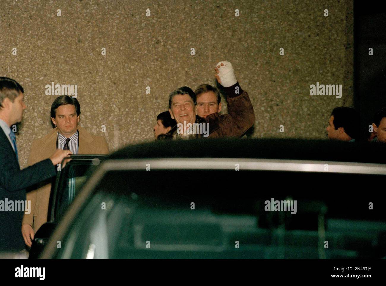 President Reagan shows his bandaged left hand to reporters and ...