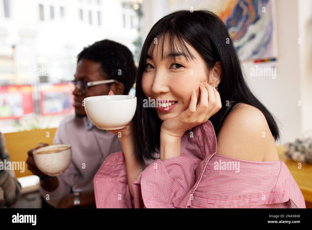 Multiracial friends girls and guys having fun laughing drinking coffee