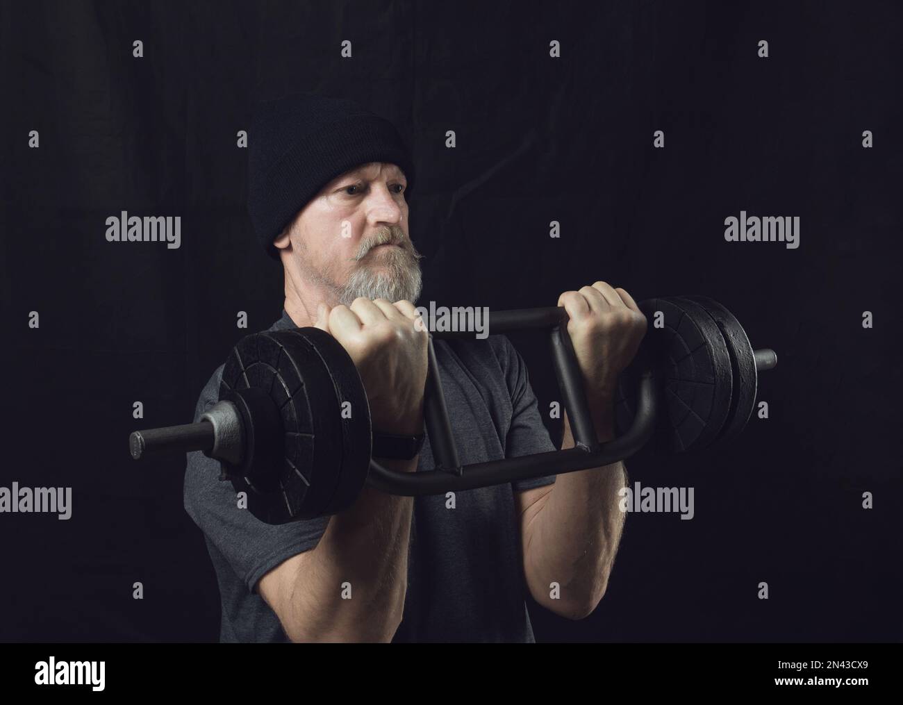 Active elderly man with a beard trains biceps with a barbell Stock ...